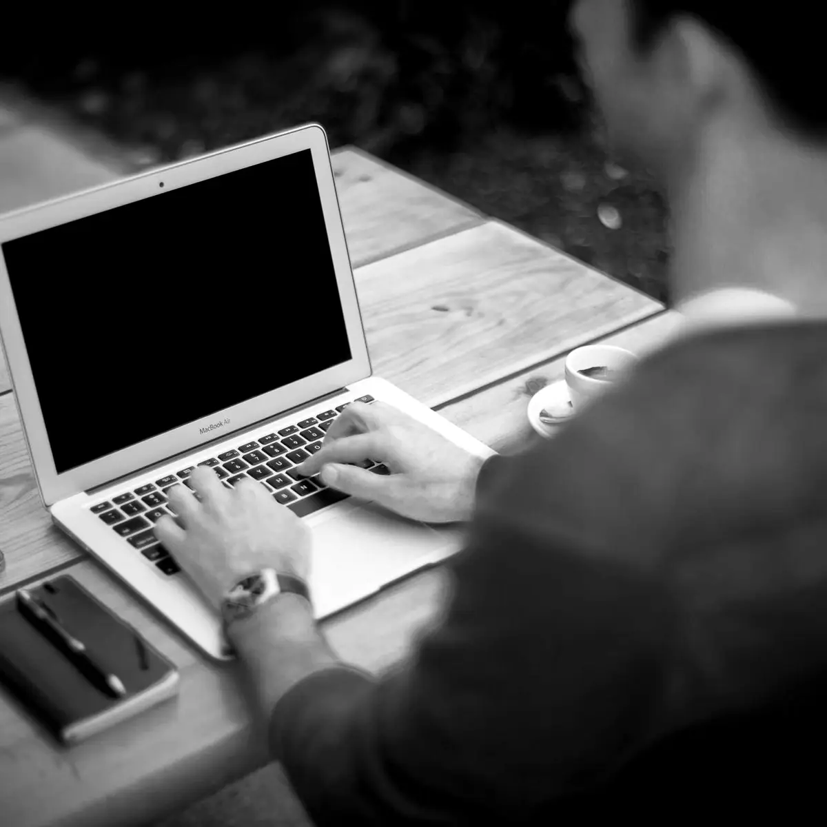 A founder working on their app on a laptop at a wooden table